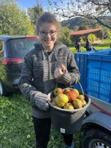 Fröhliches Mädchen mit einem Eimer voller Äpfel.